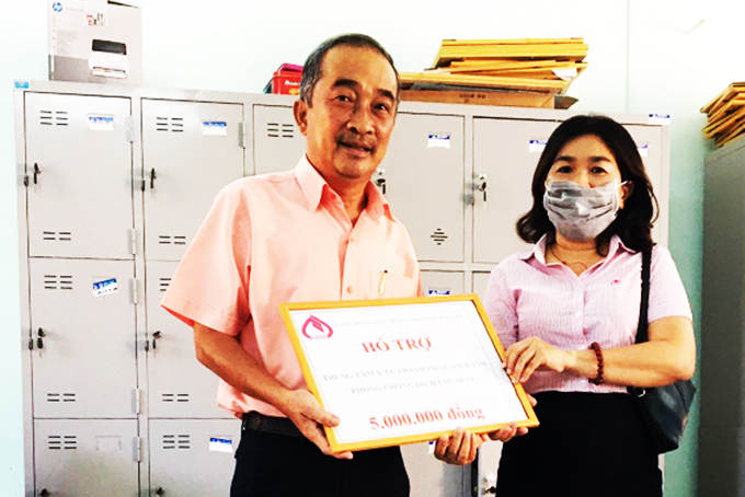 Đại diện Công đoàn bộ phận Phòng Giao dịch NHCSXH  TP. Cam Ranh (bìa phải) trao tiền hỗ trợ cho Trung tâm Y tế thành phố.
