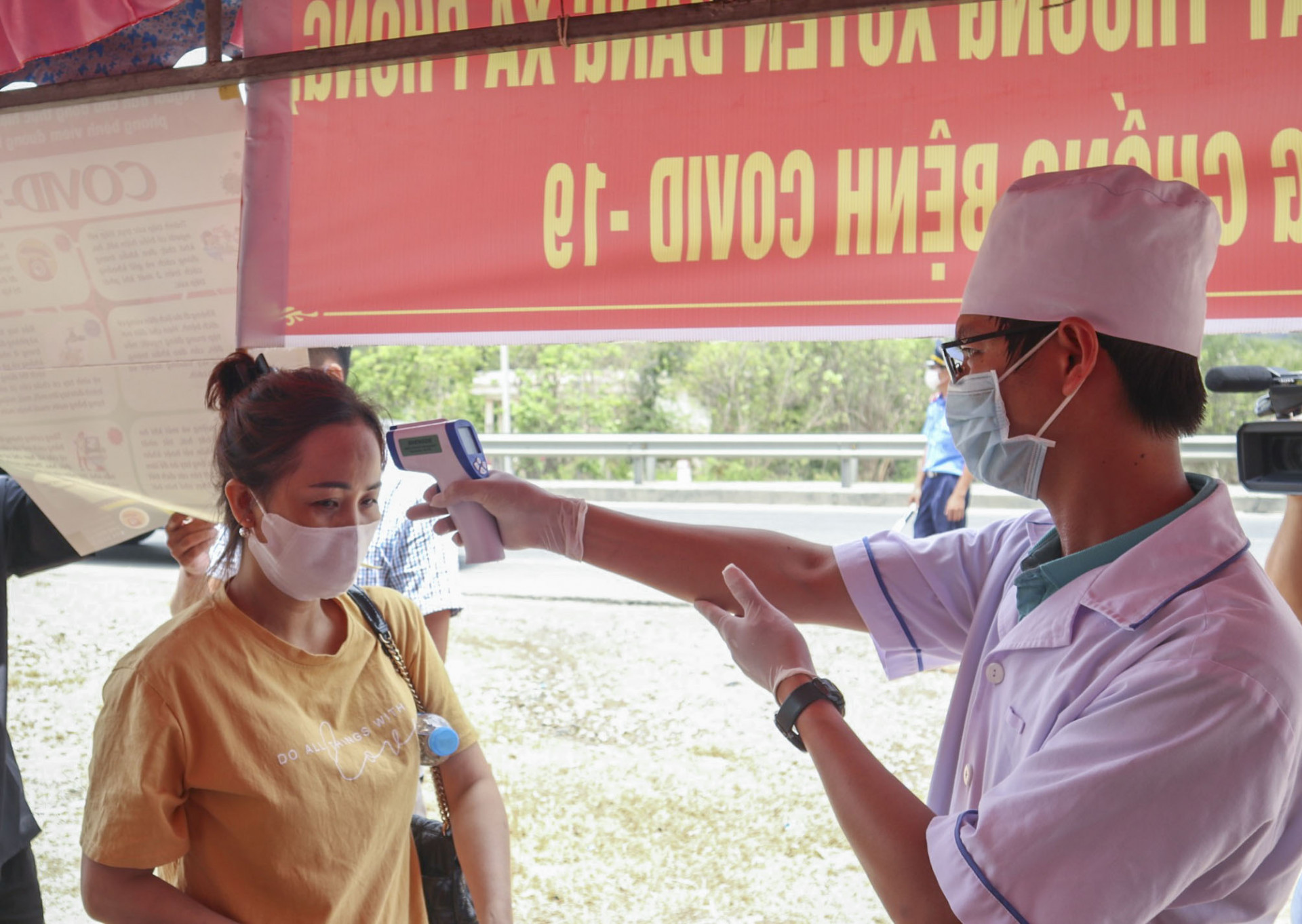 Nhân viên y tế kiểm tra thân nhiệt khách lưu thông qua Quốc Lộ 1 ở trạm Kiểm tra y tế TP. Cam Ranh