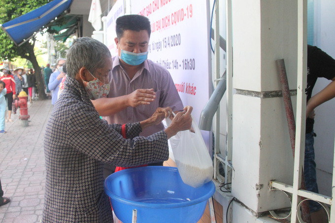  Thành viên của Ban tổ chức chương trình ATM gạo hỗ trợ một người già nhận gạo