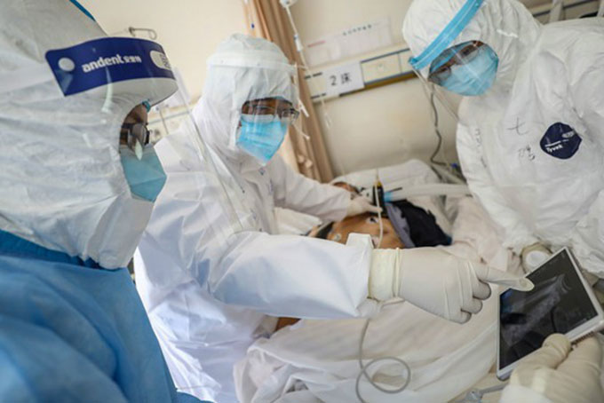 Bác sĩ tại một bệnh viện ở Vũ Hán khám cho một bệnh nhân Covid-19. Ảnh: AFP.