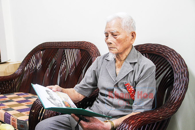 Đại tá Trần Văn Thà xem những hình ảnh về một thời tham gia kháng chiến.