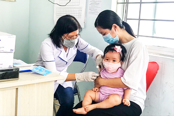 Cán bộ Trạm Y tế phường Phước Long tiêm chủng cho trẻ. 