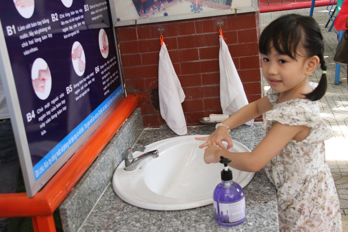 Child at Ly Tu Trong Nursery School washing her hands to prevent COVID-19