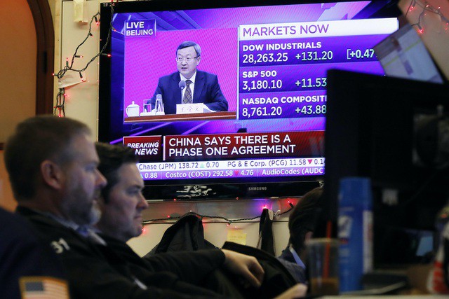 Các nhân viên tại sàn giao dịch chứng khoán New York ngồi trước màn hình chiếu bản tin quan chức Trung Quốc thảo luận về thỏa thuận thương mại với Mỹ. (Ảnh: AFP).