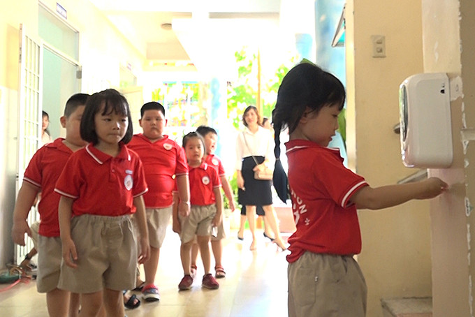 Children at 8-3 Nursery School washing hands with automatic hand sanitizer dispenser