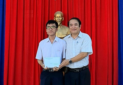 Hiệu trưởng Trường THPT Chuyên Lê Quý Đôn tặng quà cho em Hồ Lê Minh Quân. 