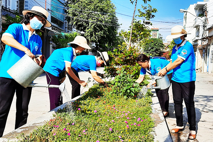 Các hội viên phụ nữ phường Phước Long chăm sóc hoa ở đường Phòng Không. 