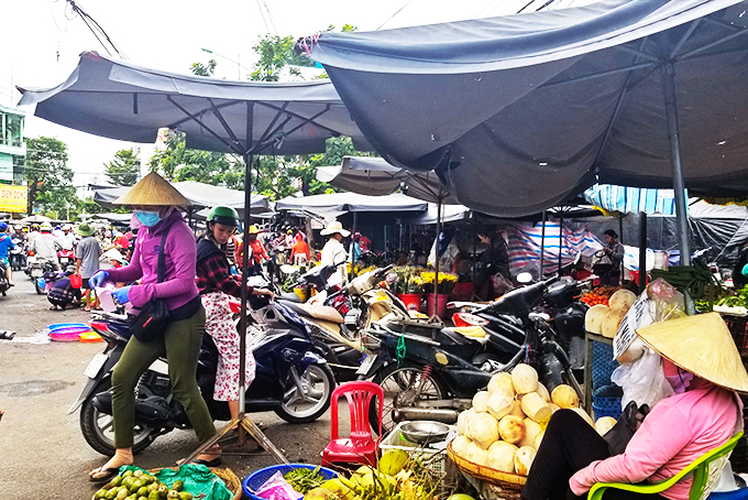 Nhiều người dân để xe máy dưới lòng đường để vào chợ Phước Thái, phường Phước Long mua hàng.  