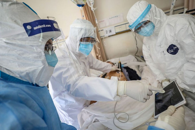 Nhân viên y tế kiểm tra tình hình sức khỏe của 1 bệnh nhân Covid-19 ở Trung Quốc. Ảnh: AFP.