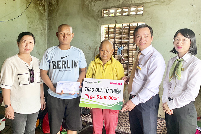 Đại diện Báo Khánh Hòa và Vietcombank Nha Trang trao tiền ủng hộ  cho hai mẹ con bà Cao Thị K.Mai.