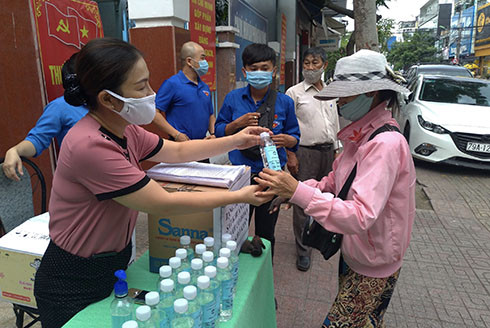 Bà Nguyễn Thị Cẩm Nhung - Chủ tịch UBMTTQ Việt Nam phường Vạn Thắng  trao dung dịch sát khuẩn cho người dân