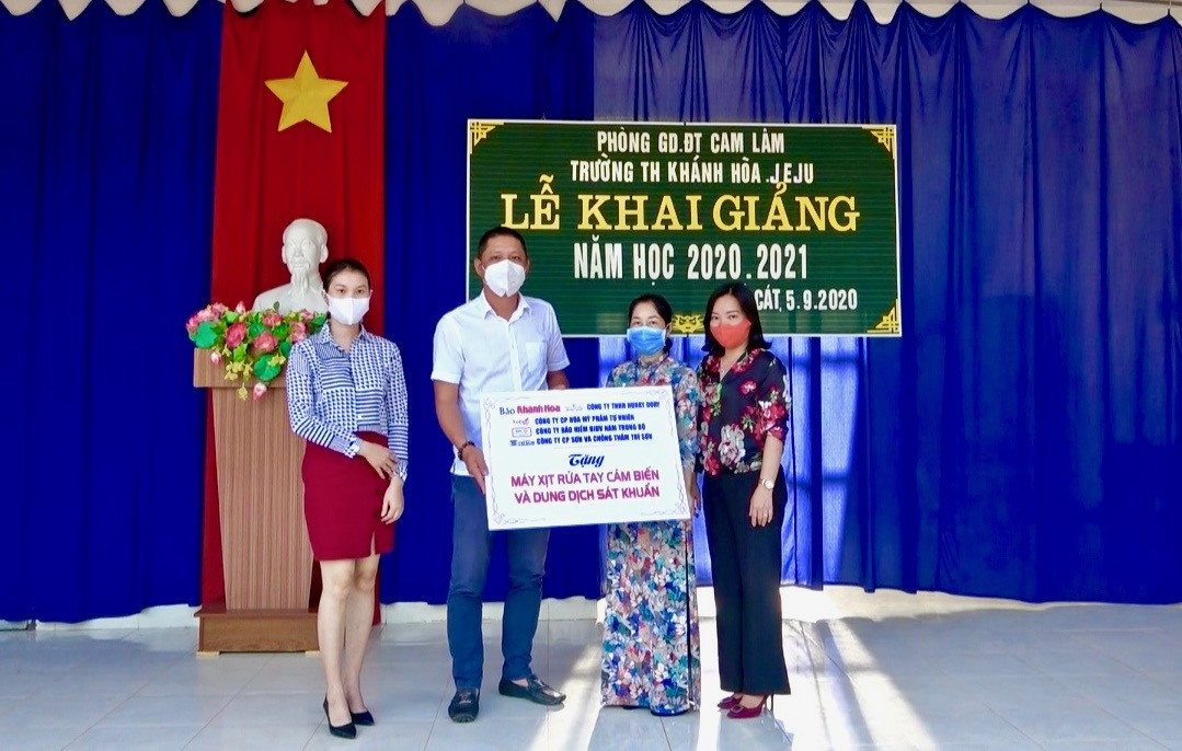 Bà Thái Thị Lệ Hằng cùng đại diện Công ty Bảo hiểm BIDV Nam Trung Bộ trao máy xịt rửa ray cảm biến và dung dịch sát khuẩn cho trường. 