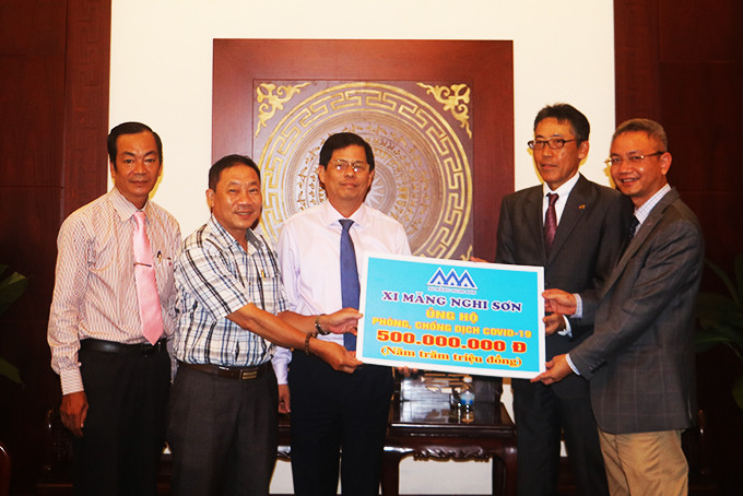 Đại diện Công ty Xi măng Nghi Sơn (bìa phải) trao tượng trưng  số tiền hỗ trợ phòng, chống dịch cho tỉnh.
