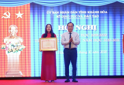 Ông Nguyễn Đắc Tài trao bằng khen của Thủ tướng Chính phủ cho cô Đào Thị Thùy Trang, Phó Hiệu trưởng Trường THPT Nguyễn Thiện Thuật (TP. Nha Trang).