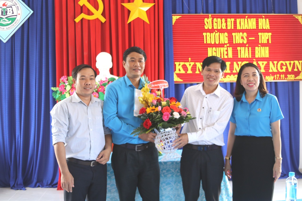 Đại diện Liên đoàn Lao động tỉnh tặng hoa chúc mừng tại Trường THCS và THPT Nguyễn Thái Bình.