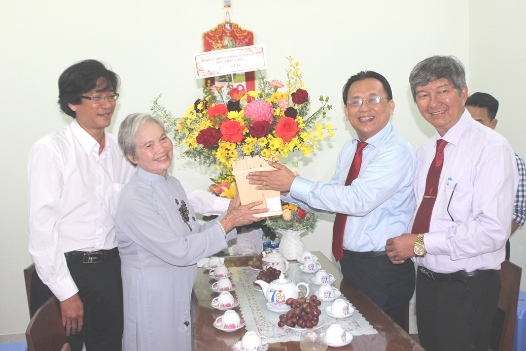 Ông Lê Hữu Hoàng (thứ 2 từ phải qua) tặng hoa chúc mừng Nhà giáo ưu tú Nguyễn Thị Huỳnh.