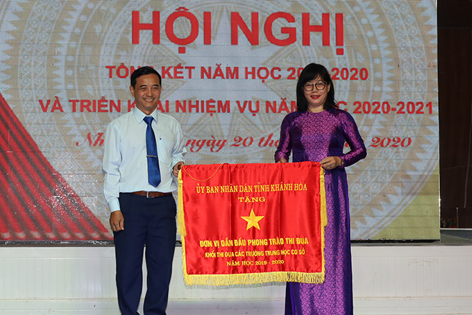 Đại diện Trường THCS Thái Nguyên (bên phải) nhận cờ thi đua xuất sắc của UBND tỉnh.