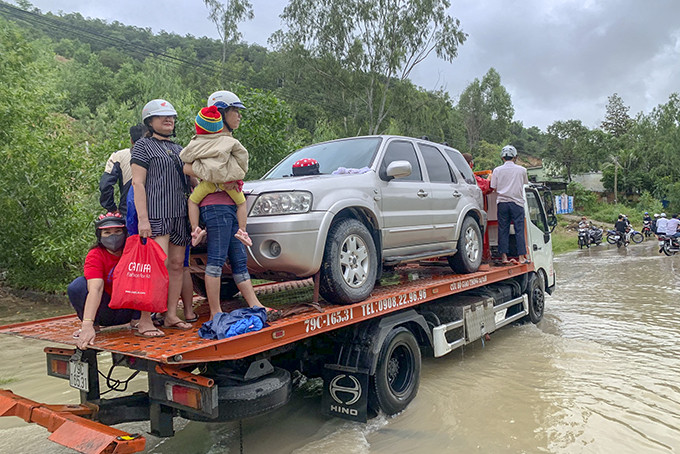 Người dân xã Vĩnh Thái đi nhờ xe cứu hộ ô tô thoát khỏi vùng ngập.