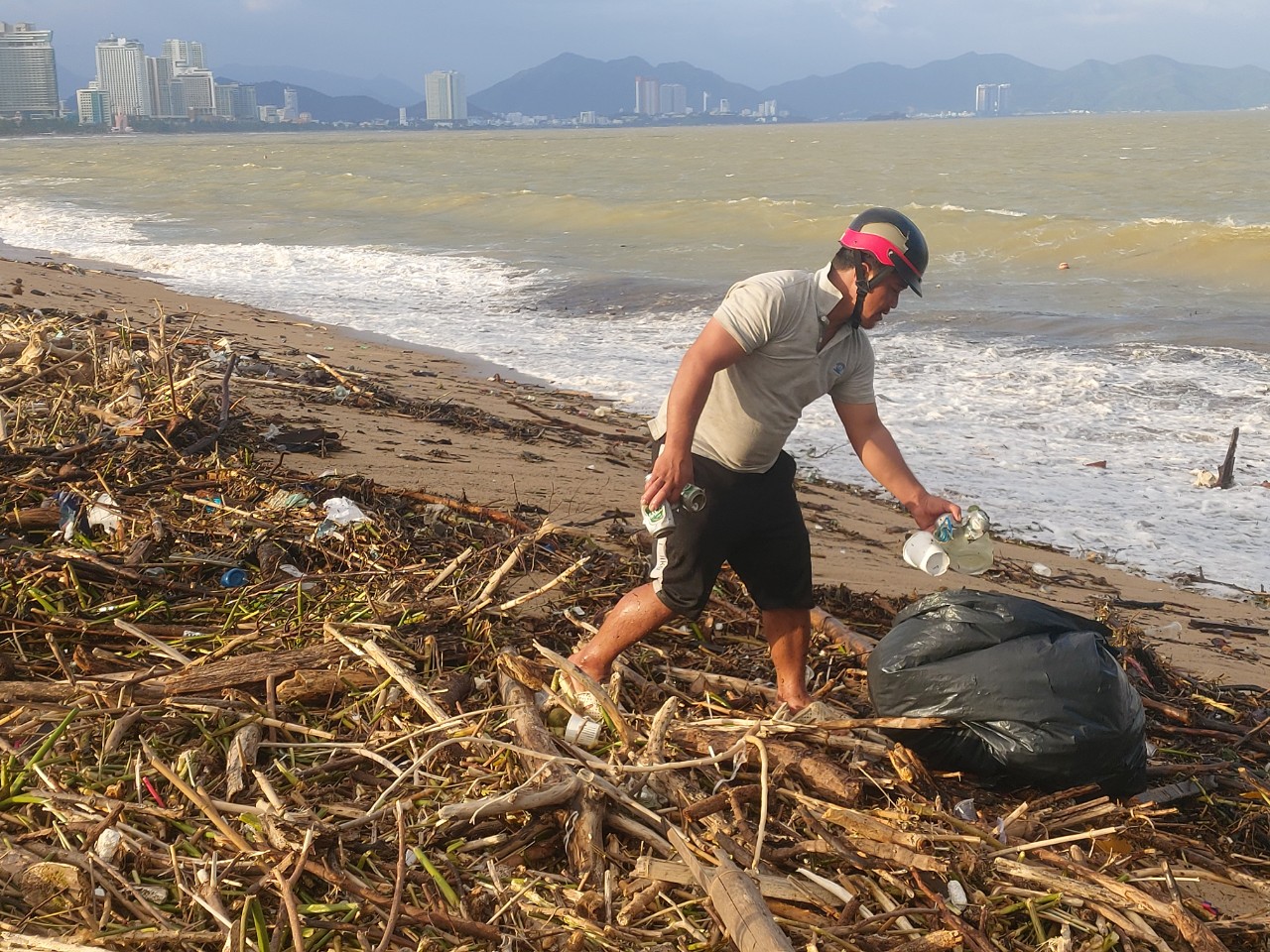 Người dân lượm nhặt ve chai trên bãi rác dạt vào bờ biển.
