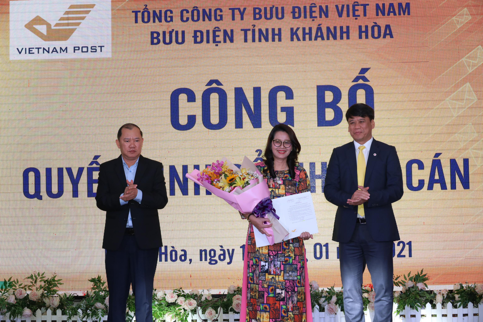 Ông Nguyễn Anh Tuân – Phó Chủ tịch UBND tỉnh Khánh Hòa (bên trái) và ông Phan Thảo Nguyên (bên phải) trao quyết định, tặng hoa chúc mừng bà Ung Thị Vân. 