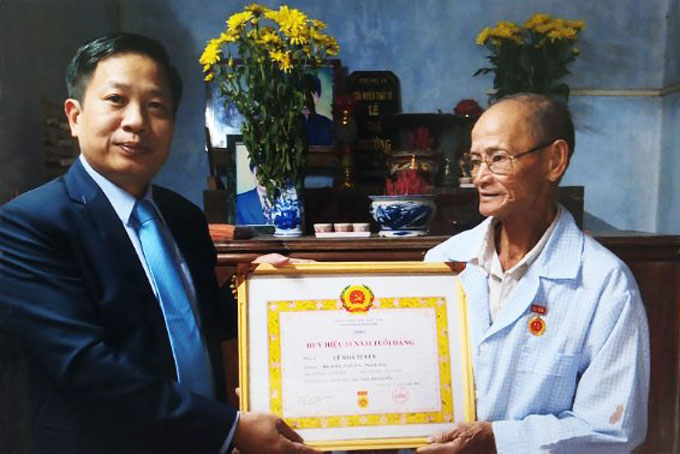 Ông Hà Quốc Trị trao huy hiệu 50 năm tuổi Đảng cho đảng viên Lê Khả Tuyên.