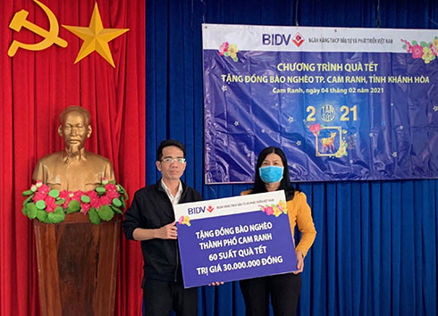 Đại diện Ngân hàng bìa trái trao tượng trưng quà Tết cho người nghèo TP. Cam Ranh