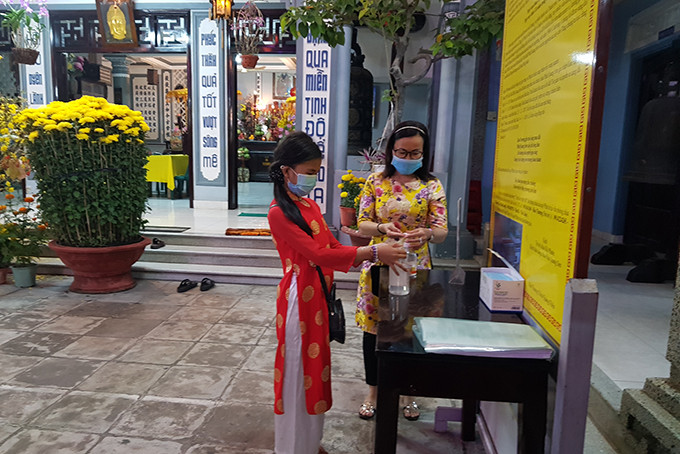 Người dân rửa tay với nước sát khuẩn trước khi vào lễ Phật tại Sắc Tứ Hội Phước (Chùa Cát)