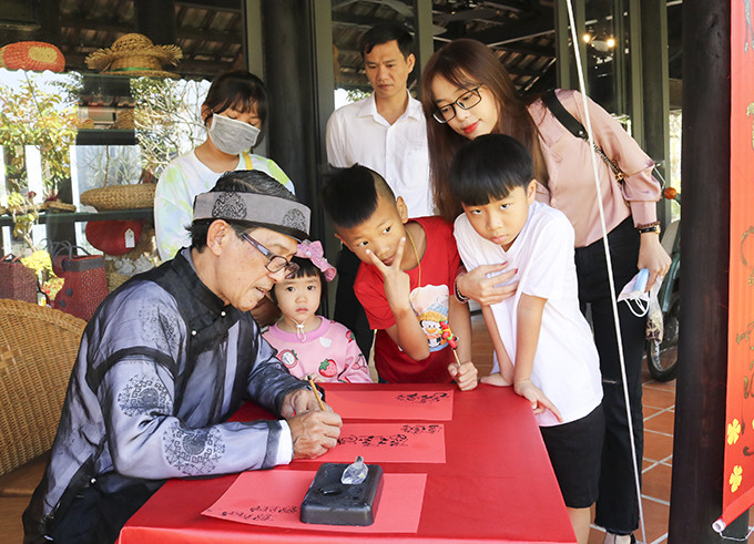 Calligrapher wearing Vietnam’s traditional costume offering beautiful writing to visitors