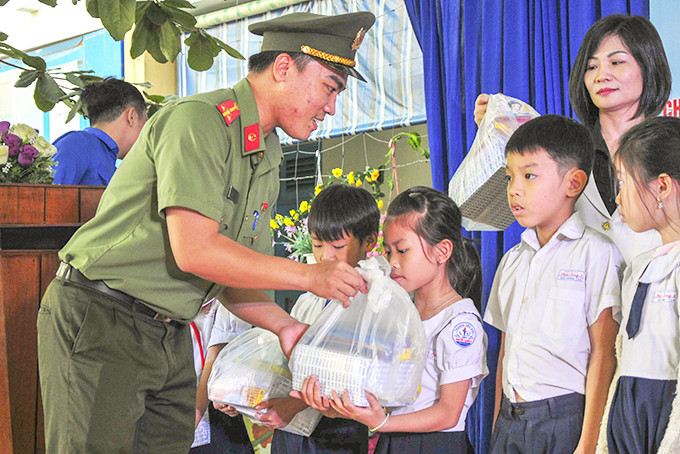 Thượng úy Lê Bá Khánh trao quà cho học sinh có hoàn cảnh khó khăn. 