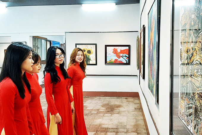Khanh Hoa University students contemplating exhibited paintings