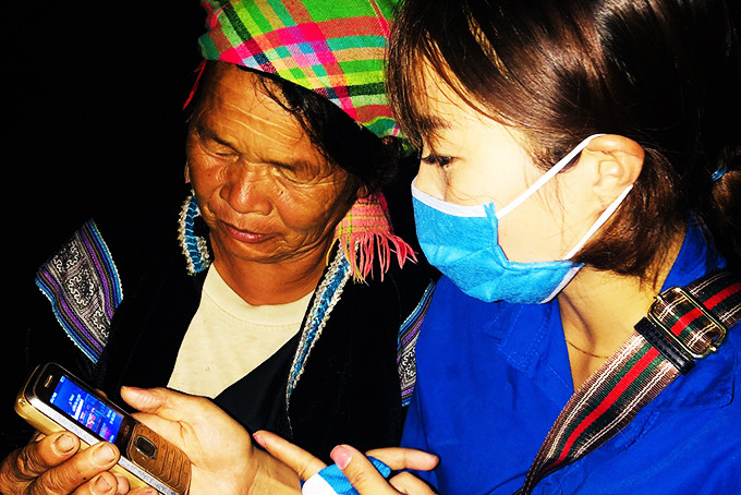 Thanh niên tình nguyện hướng dẫn một người dân tộc thiểu số ở Lai Châu cài đặt Bluezone.