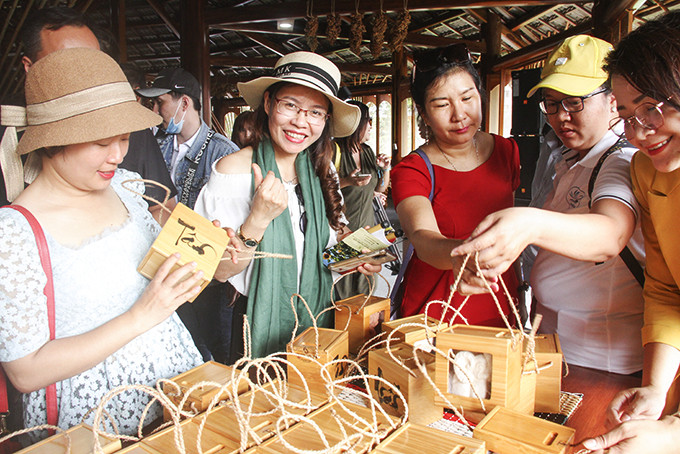 Khách du lịch nội địa vẫn là đối tượng chính của du lịch Khánh Hòa năm 2021. Trong ảnh: Du khách xem hàng lưu niệm tại Làng nghề Trường Sơn.