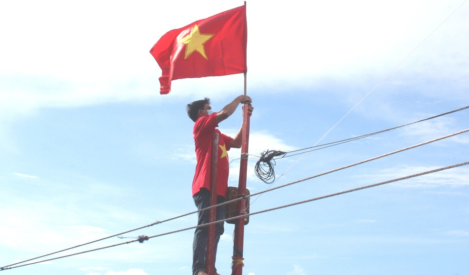 Ngư dân treo cờ tổ quốc lên tàu cá.