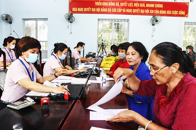 Cán bộ Ngân hàng Chính sách xã hội tỉnh giao dịch tại xã Vĩnh Thạnh. (Ảnh chụp ngày 16-3-2021)
