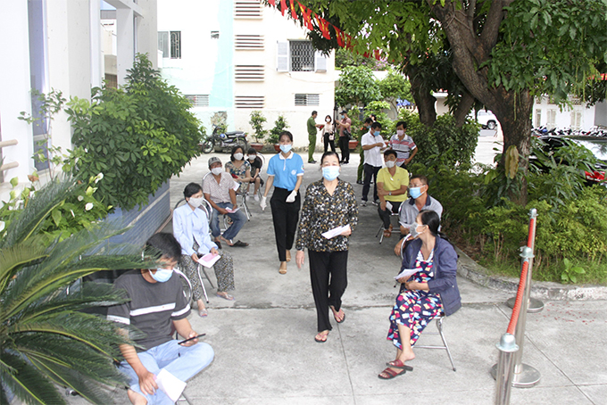 Cử tri ngồi giãn cách đợi vào bỏ phiếu bầu cử ở khu vực bỏ phiếu số 4 phường Lộc Thọ, TP. Nha Trang. Ảnh: X.T
