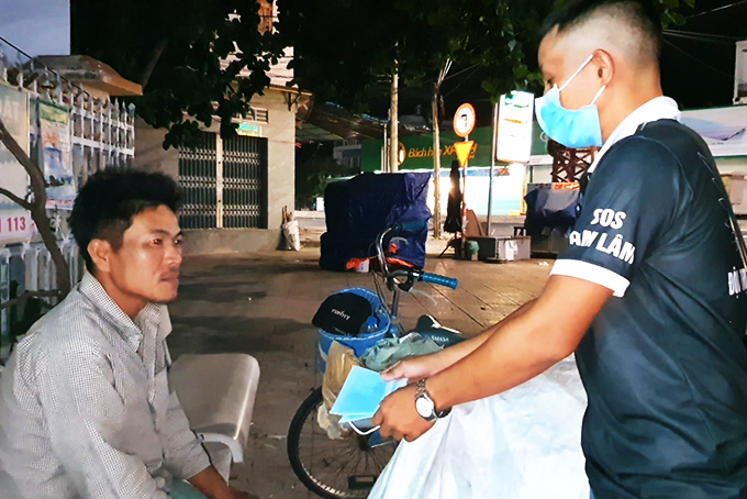 Thành viên Đội SOS Cam Lâm tặng khẩu trang cho người dân.