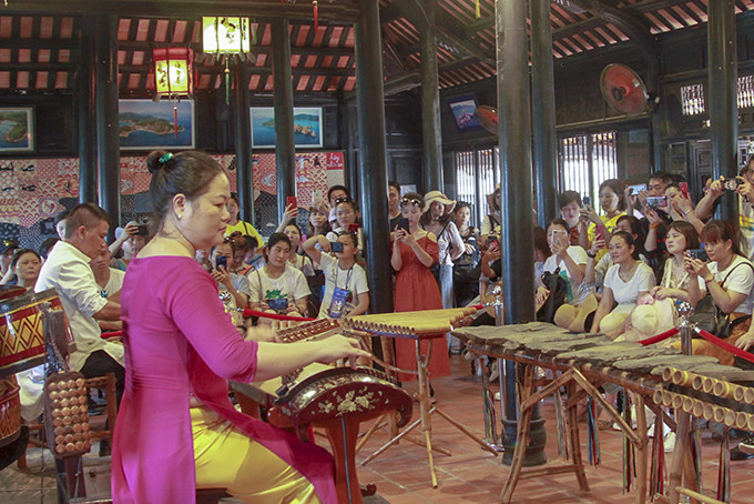 Biểu diễn nhạc cụ dân tộc phục vụ khách du lịch tại Hội quán Hòn Chồng. (Ảnh chụp năm 2019)