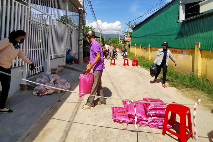 Người dân trong khu phong tỏa ở xã Suối Tân  nhận lương thực do UBND xã hỗ trợ. Ảnh: BÍCH LA