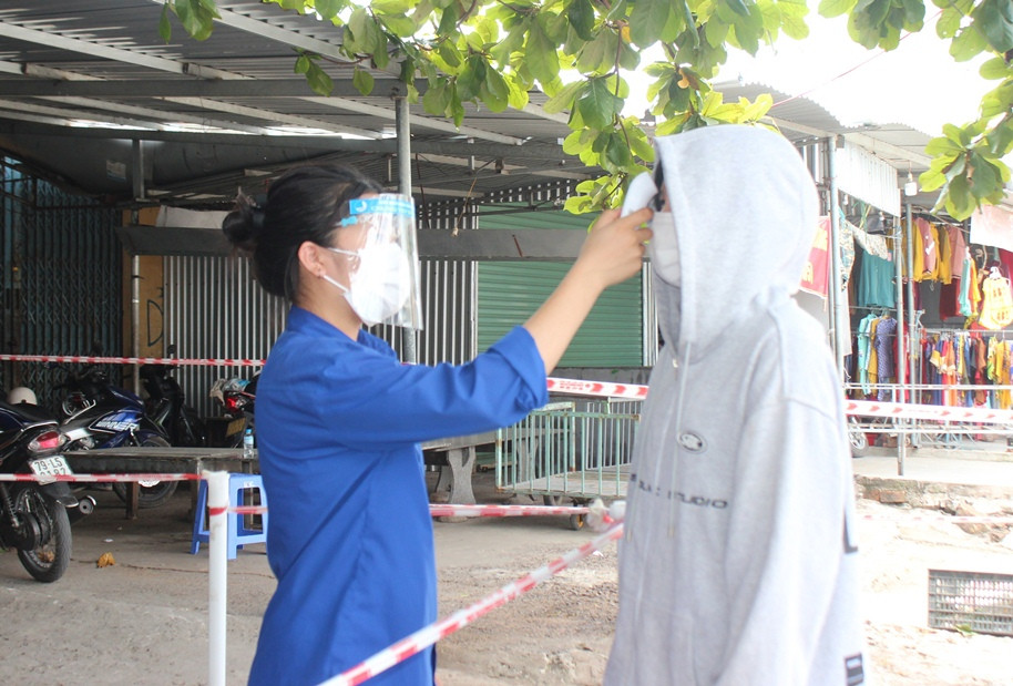 Người dân vào chợ xã Vạn Thắng mua hàng hóa được đo thân nhiệt,khai báo y tế.