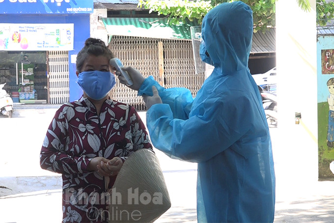 A woman in Vinh Phuoc Ward, Nha Trang City having body temperature checked before getting rapid test 