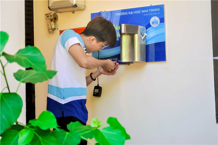 A student of Nha Trang University installing hand sanitizer dispenser
