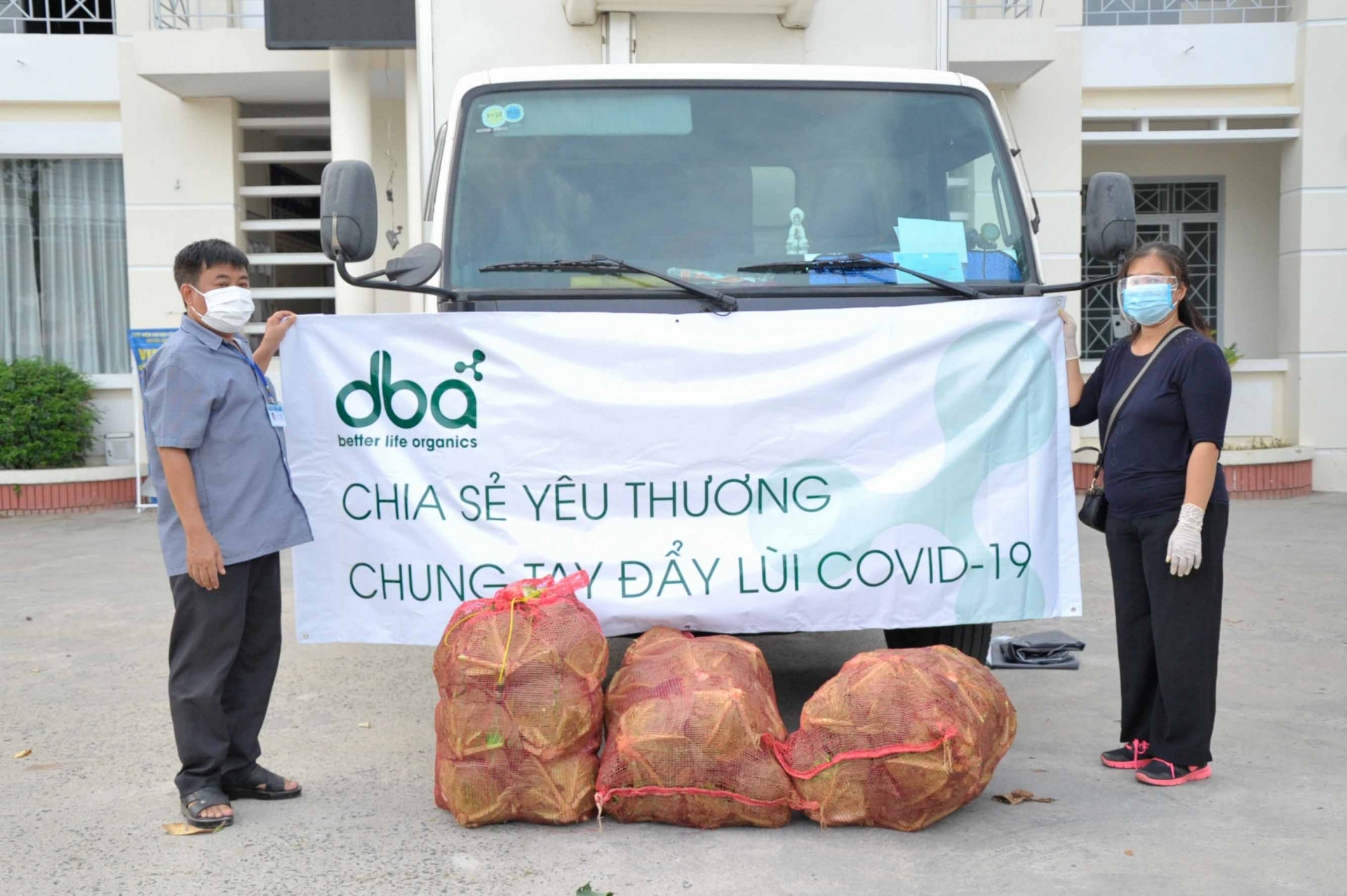 Đại diện Công ty DBA (bên phải) bàn giao nông sản cho UBND xã Vĩnh Ngọc để hỗ trợ người dân