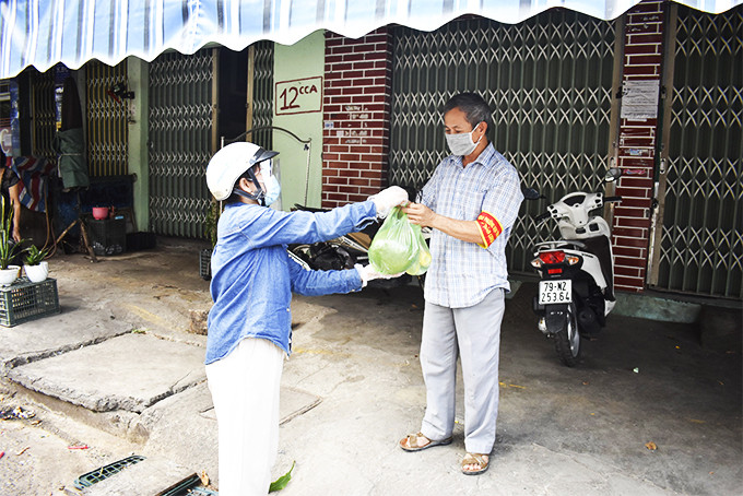 Một thành viên tổ cứu trợ ở phường Vạn Thạnh giao hàng mua hộ cho người dân.