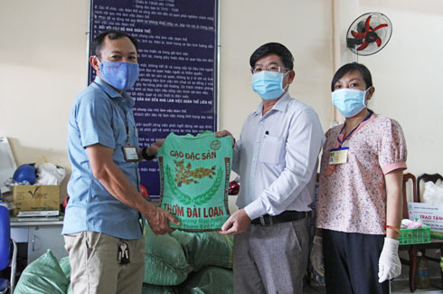 Ông Lê Hoàng Triều - Phó Tổng Biên tập Báo Khánh Hòa (đứng giữa) trao gạo cho đại diện phường Vĩnh Phước..