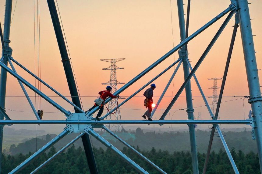 Công nhân bảo trì đường dây điện ở Trung Quốc. Ảnh: AFP