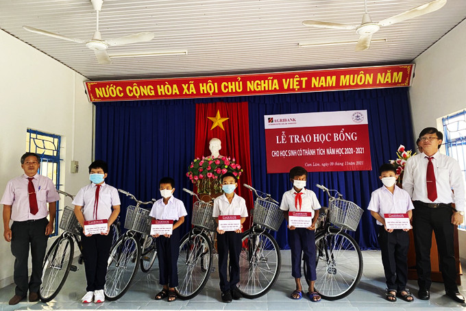 Lãnh đạo Agribank Chi nhánh huyện Cam Lâm và lãnh đạo Phòng Giáo dục và Đào tạo huyện trao xe đạp cho học sinh.