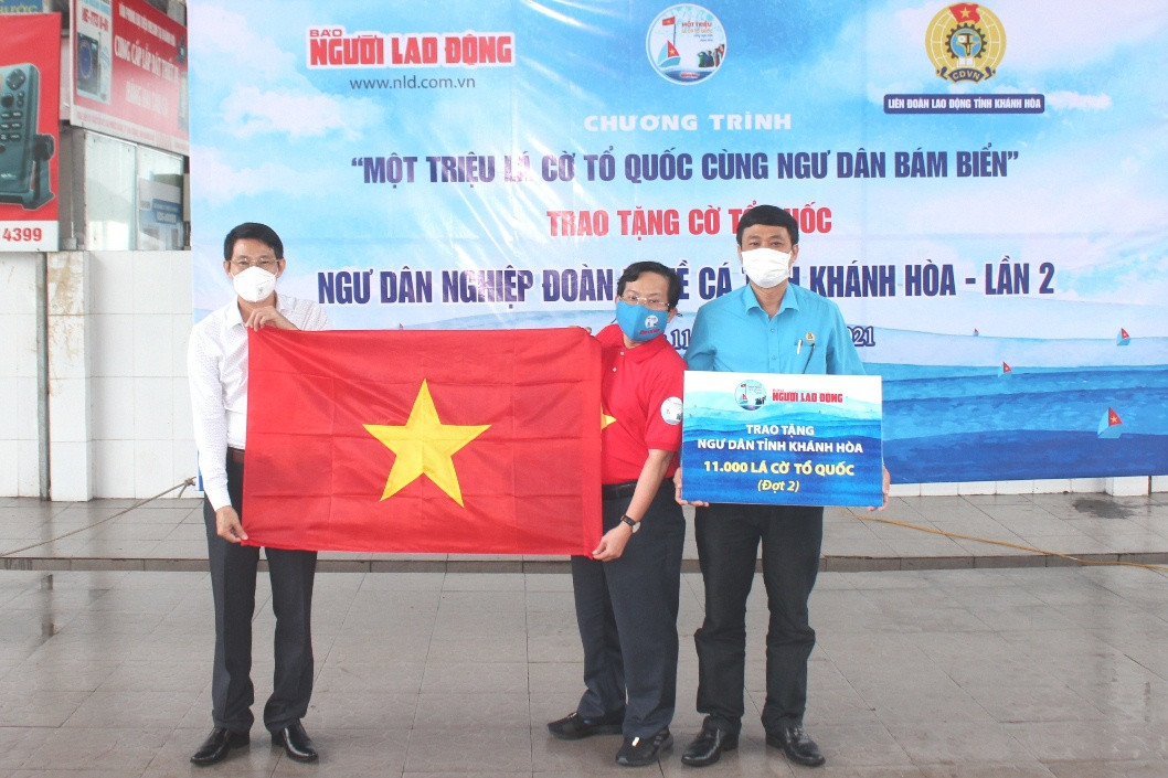 Ông Đinh Văn Thiệu và đại diện Liên đoàn Lao động tỉnh tiếp nhận cờ Tổ quốc do Báo Người Lao Động trao tặng cho ngư dân.