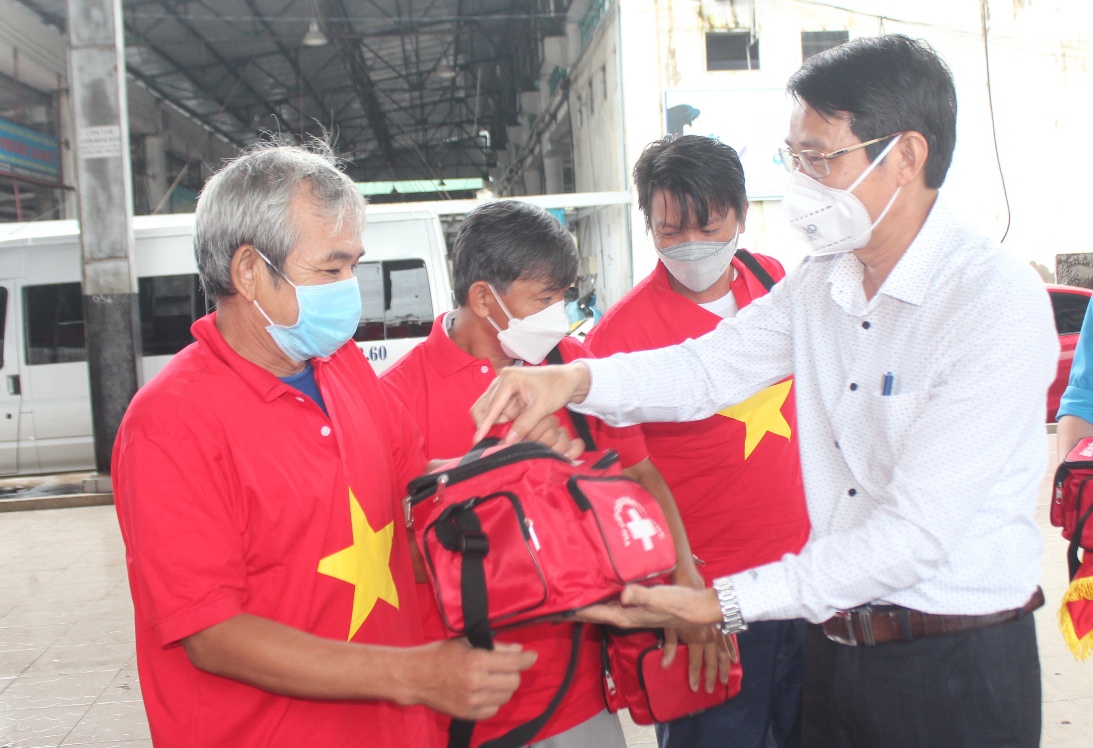 Ông Đinh Văn Thiệu trao cờ và túi thuốc cho ngư dân.