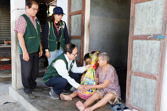 Ông Trương Tân Minh, Chủ tịch Hội cùng các thành viên trao quà cho người nghèo ở huyện Cam Lâm (Ảnh chụp tháng 2/2021)