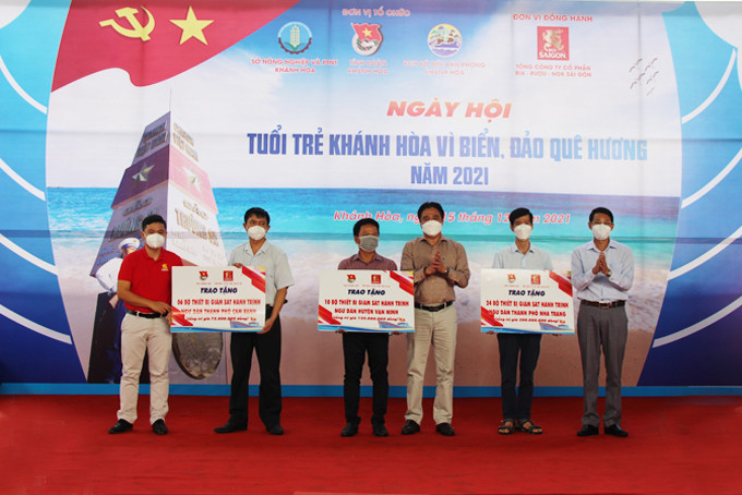 Đồng chí Nguyễn Khắc Toàn, đồng chí Đinh Văn Thiệu và đại diện đơn vị tài trợ trao tượng trưng thiết bị giám sát hành trình tàu cá cho đại diện ngư dân các địa phương.